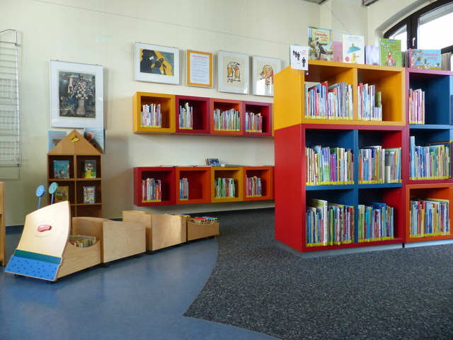 Das Bild zeigt einen Raum mit Regalen. Die Bücher sind für Kinder.