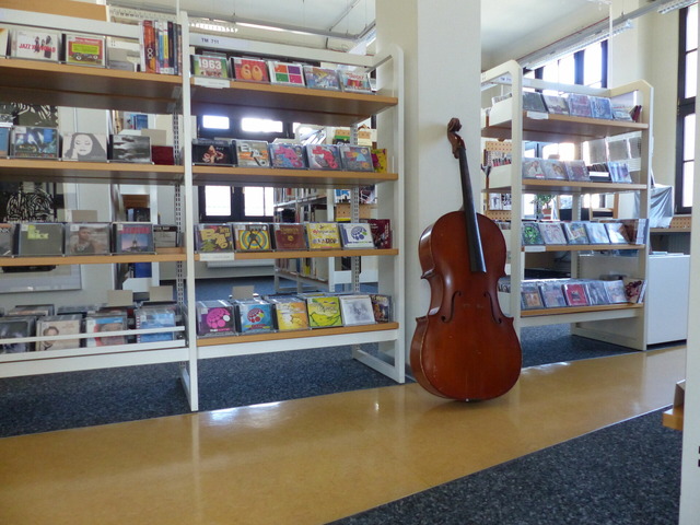 Das Bild zeigt ein Regal mit CDs und einen Kontrabass.