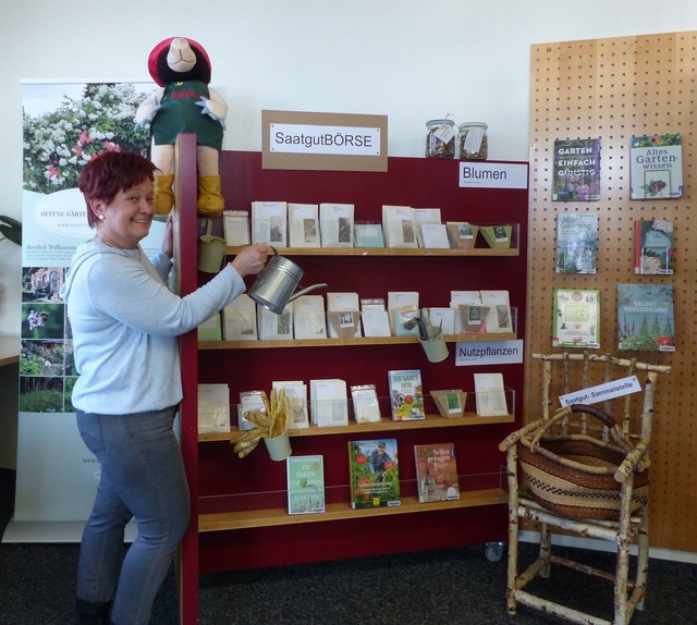 Das Bild zeigt eine Person. Die Person zeigt auf ein Regal.